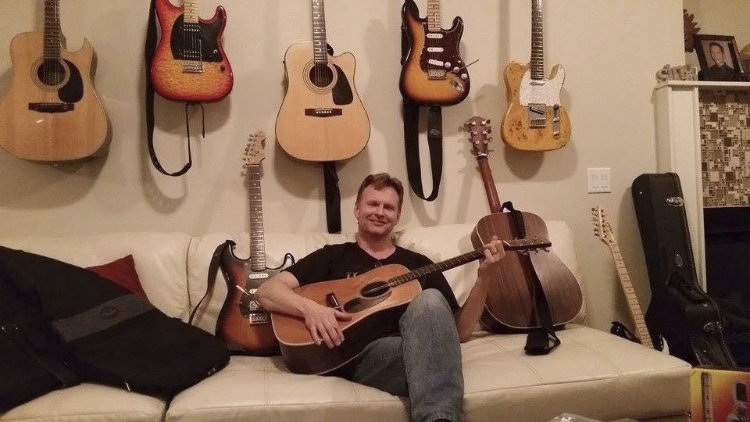 Jim Rhindress sitting with several guitars